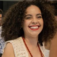 The picture shows a curly hair woman smiling.