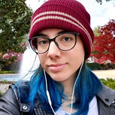 A photo of Laura Vieira: white, glasses, blue hair.