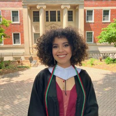 The photo shows a curly hair woman smiling.