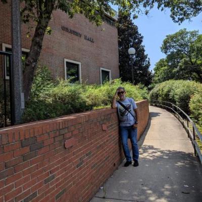 man standing if front of gilbert hall building