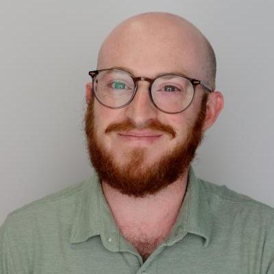 smiling man with glasses and red beard wearing green shirt 